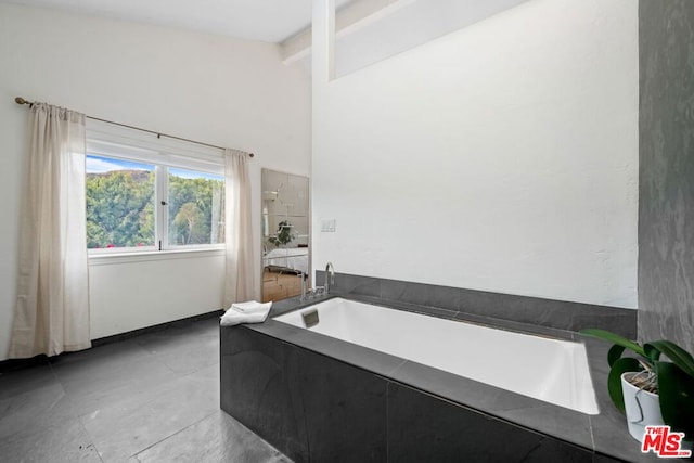 bathroom with beam ceiling and a tub to relax in