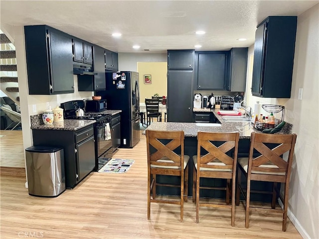 kitchen with range hood, a sink, light wood-type flooring, a peninsula, and black appliances