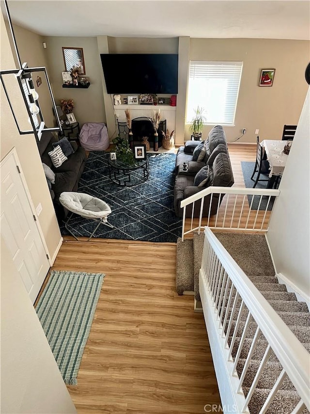 living area with stairs, a fireplace, and wood finished floors