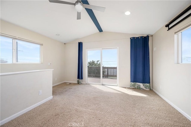 empty room featuring ceiling fan, carpet floors, lofted ceiling with beams, and a healthy amount of sunlight