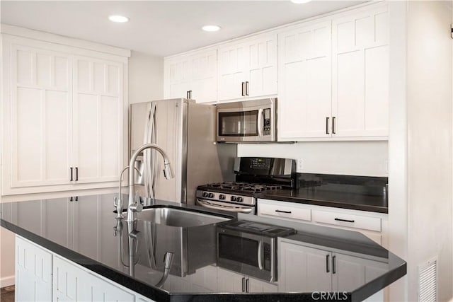 kitchen featuring white cabinetry, appliances with stainless steel finishes, sink, and an island with sink