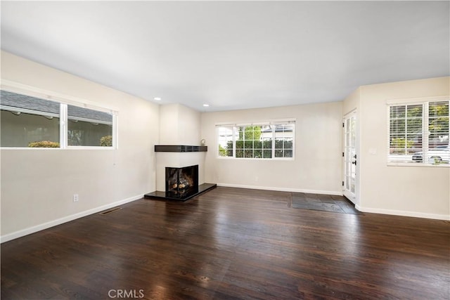 unfurnished living room with a healthy amount of sunlight and dark hardwood / wood-style floors