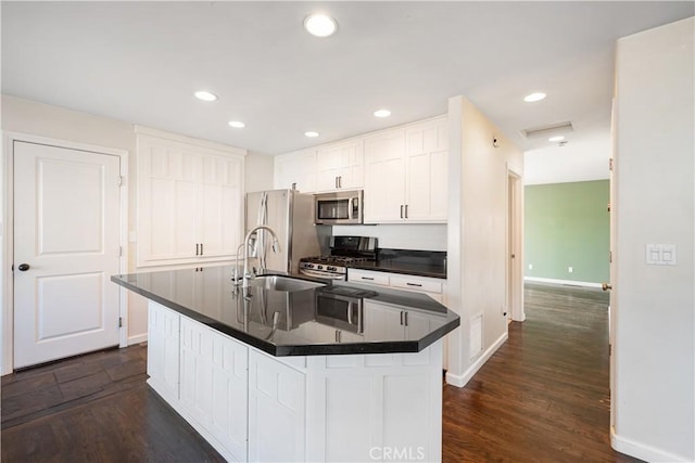 kitchen with an island with sink, sink, white cabinets, dark hardwood / wood-style flooring, and stainless steel appliances