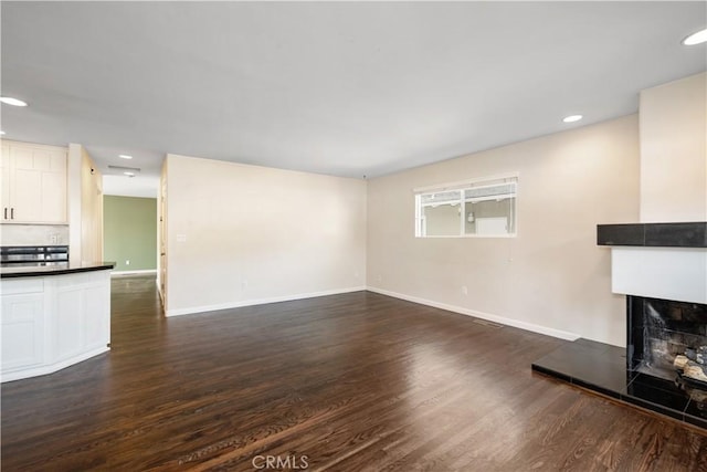 unfurnished living room with a multi sided fireplace and dark hardwood / wood-style floors