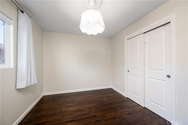 unfurnished bedroom with dark wood-type flooring and a closet