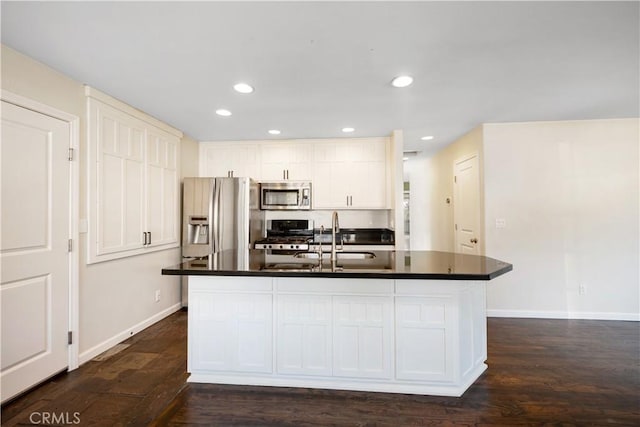 kitchen featuring stainless steel appliances, an island with sink, dark hardwood / wood-style floors, and white cabinetry