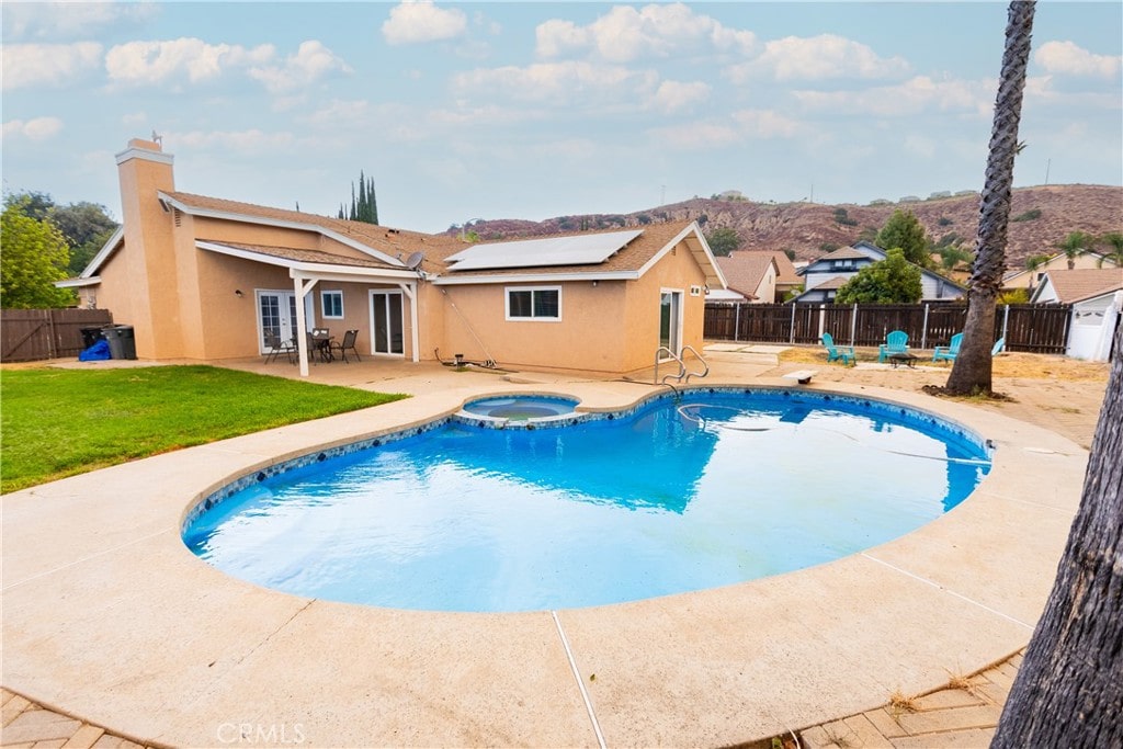 view of swimming pool featuring a lawn, a patio area, and an in ground hot tub