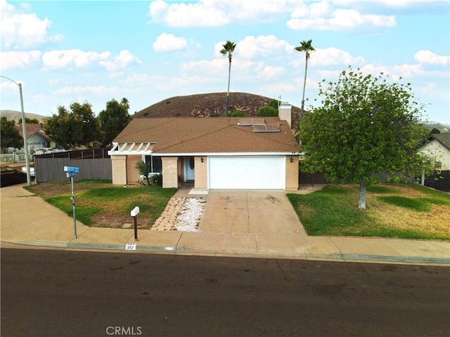 view of front of property featuring solar panels, a garage, and a front lawn