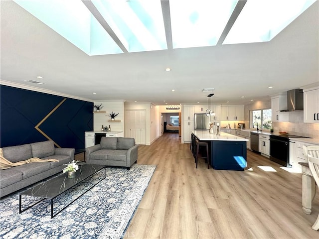 living room with a skylight, light hardwood / wood-style flooring, and ornamental molding