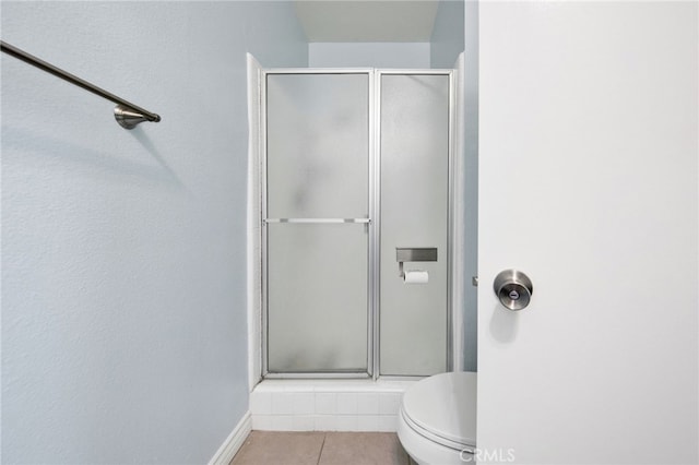 bathroom featuring walk in shower, tile patterned floors, and toilet