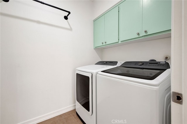 laundry area featuring washer and clothes dryer, cabinets, and dark tile patterned floors