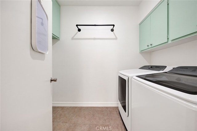 clothes washing area featuring light tile patterned flooring, washer and dryer, and cabinets