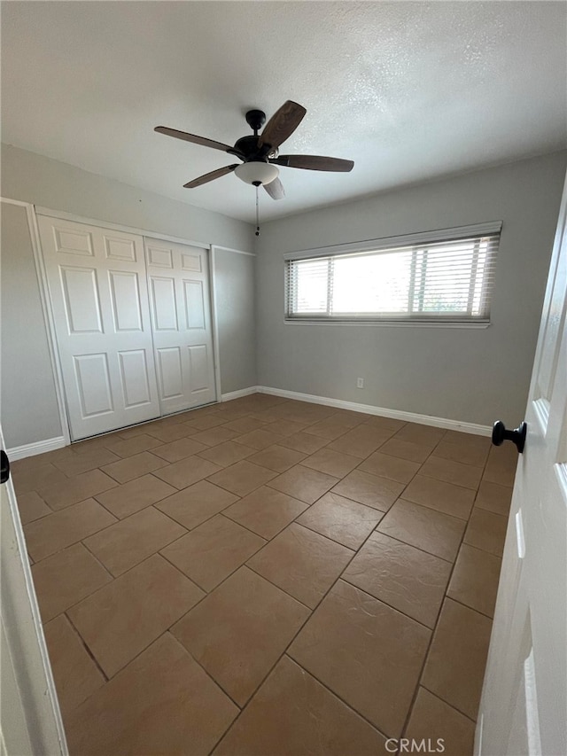 unfurnished bedroom featuring multiple windows, tile patterned flooring, ceiling fan, and a closet