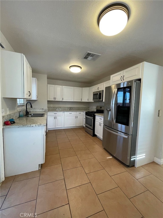 kitchen featuring light stone countertops, sink, stainless steel appliances, and white cabinets