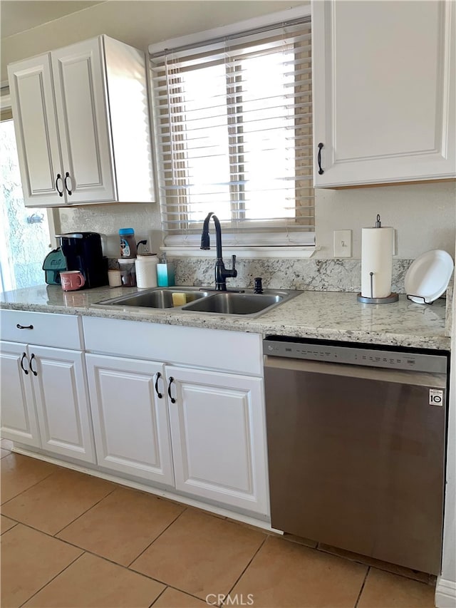 kitchen with dishwasher, white cabinetry, light tile patterned flooring, and sink