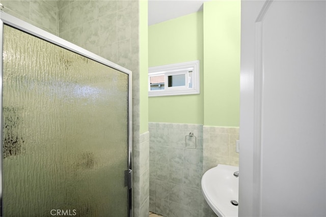 bathroom featuring sink, walk in shower, and tile walls