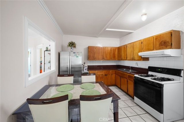 kitchen with white stove, sink, crown molding, decorative backsplash, and stainless steel fridge