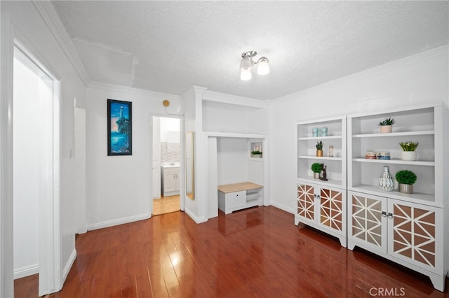 interior space featuring a textured ceiling, hardwood / wood-style flooring, and crown molding