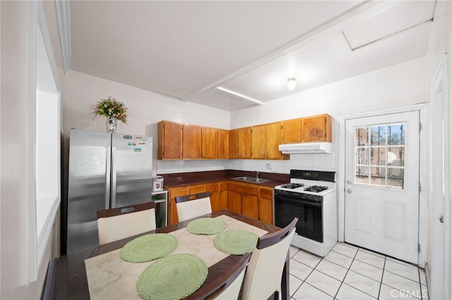 kitchen featuring appliances with stainless steel finishes, backsplash, light tile patterned floors, and sink