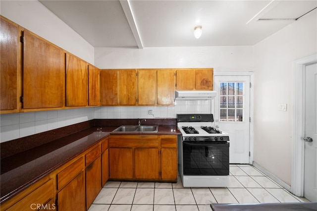 kitchen featuring white range oven, light tile patterned floors, sink, and tasteful backsplash