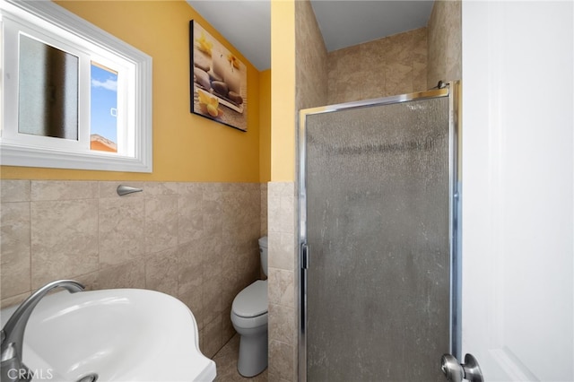 bathroom with toilet, a shower with shower door, sink, and tile walls