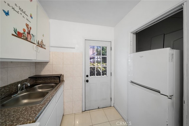 kitchen with white cabinets, white refrigerator, sink, tile walls, and light tile patterned flooring