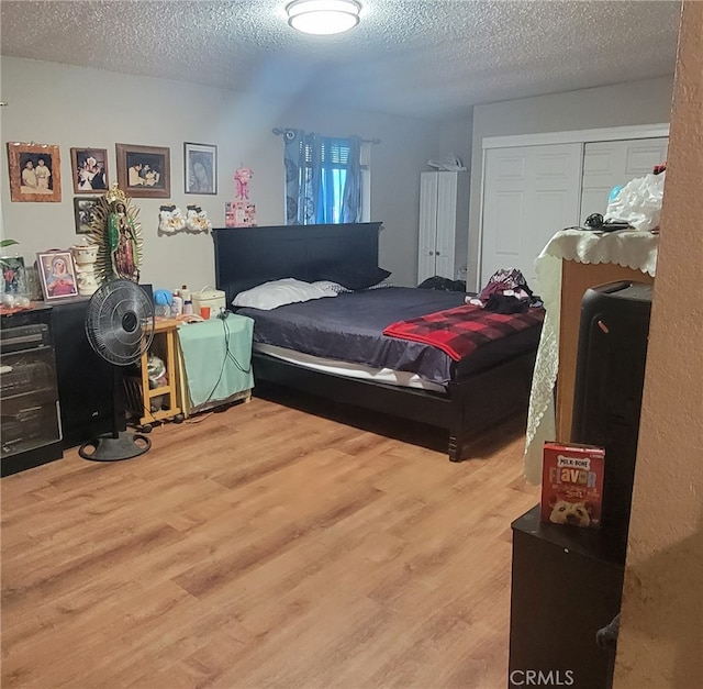 bedroom with a textured ceiling, hardwood / wood-style floors, and a closet