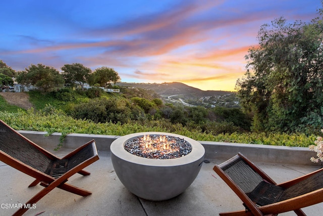 patio terrace at dusk featuring a mountain view and an outdoor fire pit