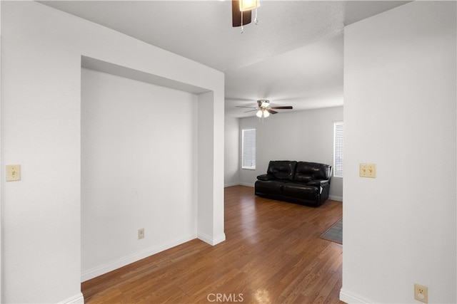 unfurnished living room featuring ceiling fan and dark wood-type flooring