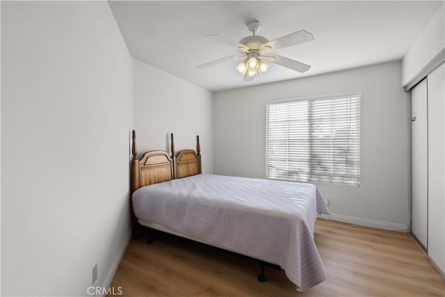 bedroom featuring light hardwood / wood-style floors, ceiling fan, and a closet