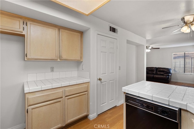 kitchen with ceiling fan, dishwasher, light hardwood / wood-style flooring, and tile counters