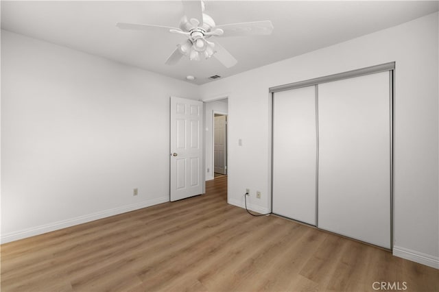 unfurnished bedroom featuring ceiling fan, light wood-type flooring, and a closet