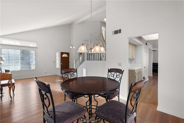 dining space with light hardwood / wood-style flooring, a notable chandelier, and high vaulted ceiling