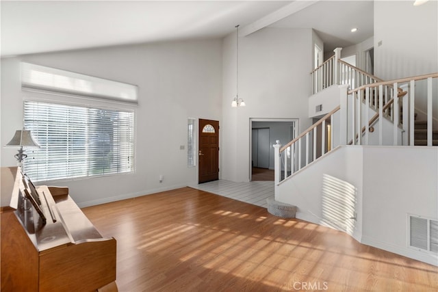 entrance foyer featuring light wood-type flooring, a notable chandelier, and high vaulted ceiling