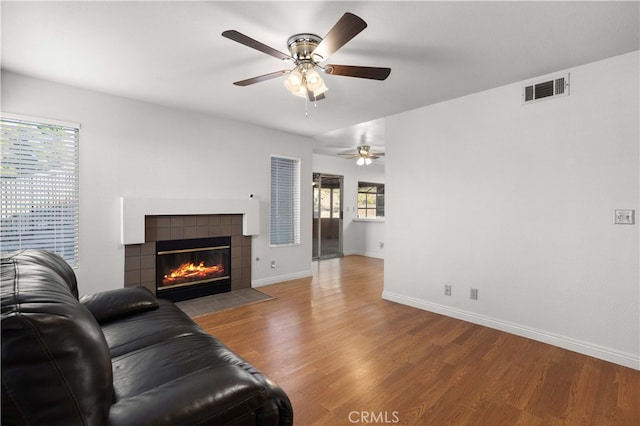 living room featuring ceiling fan, a tile fireplace, and hardwood / wood-style floors