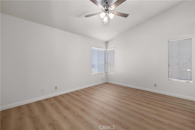 spare room with light hardwood / wood-style flooring, vaulted ceiling, and ceiling fan