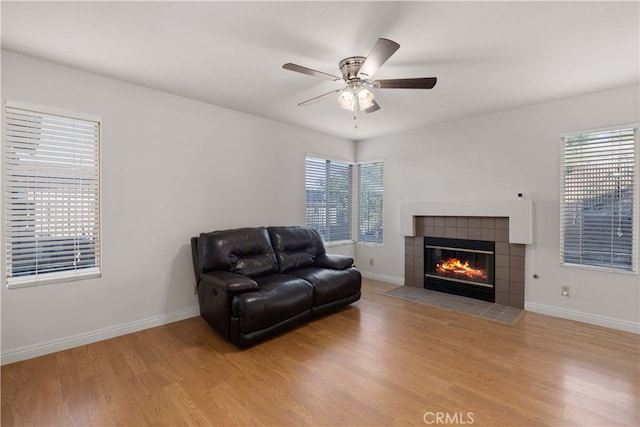 living room featuring light wood-type flooring, a fireplace, ceiling fan, and a wealth of natural light