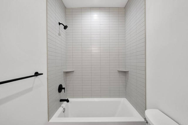 bathroom with tiled shower / bath combo and toilet