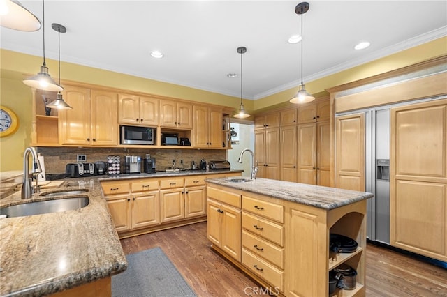 kitchen with an island with sink, pendant lighting, built in appliances, and light brown cabinetry