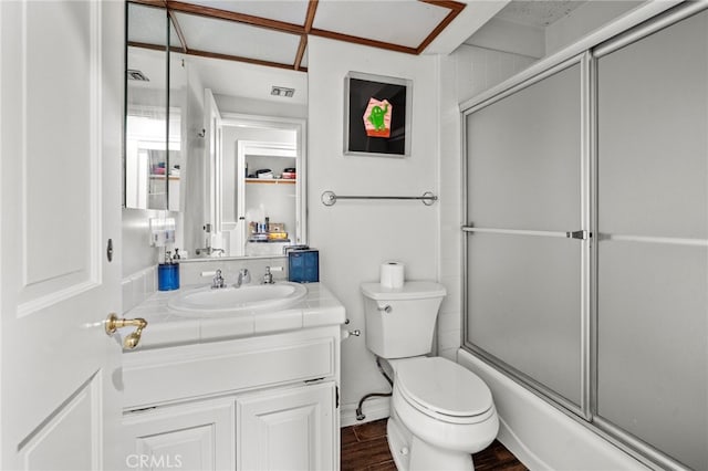 full bathroom featuring hardwood / wood-style floors, bath / shower combo with glass door, vanity, and toilet