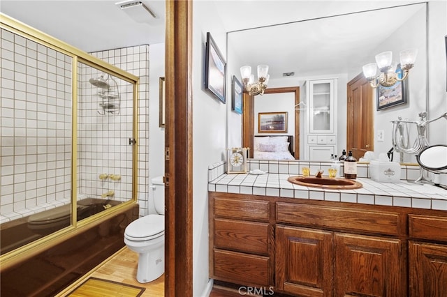 full bathroom featuring tasteful backsplash, vanity, enclosed tub / shower combo, toilet, and hardwood / wood-style floors