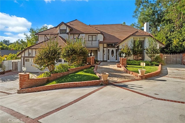 view of front of property featuring a balcony, a garage, and a front yard