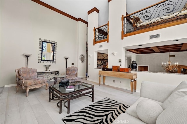 living room featuring a towering ceiling, a chandelier, and light hardwood / wood-style floors