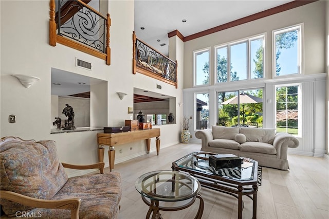 living room featuring a towering ceiling, plenty of natural light, and light wood-type flooring