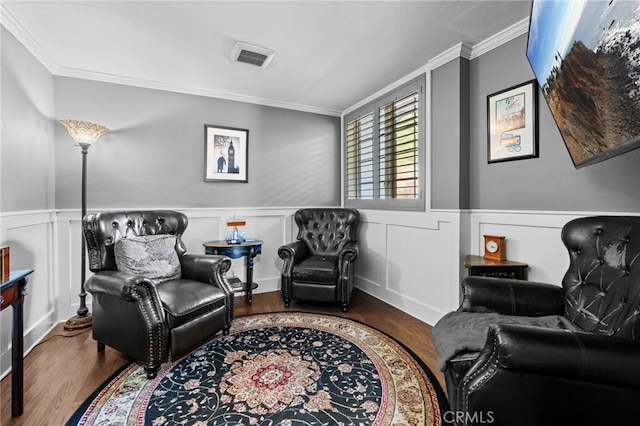 sitting room with wood-type flooring and crown molding