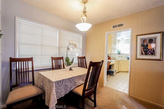 carpeted dining space with a textured ceiling