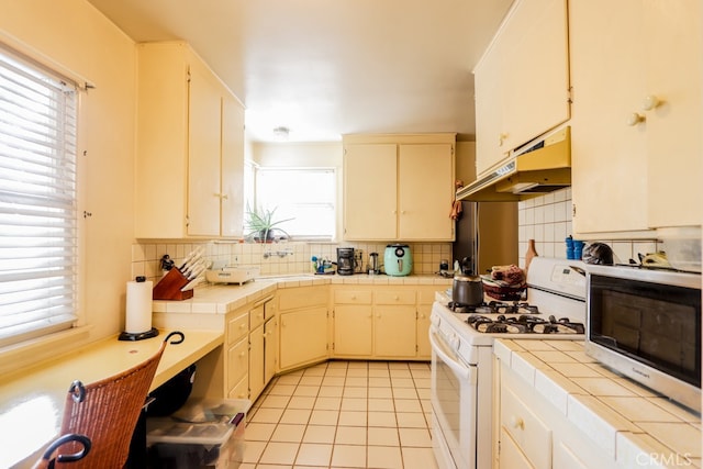 kitchen featuring a wealth of natural light, backsplash, and white range with gas cooktop