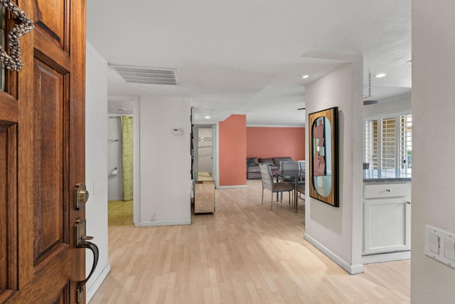 corridor with light hardwood / wood-style flooring and ornamental molding