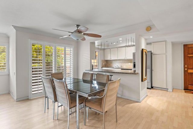 dining room with crown molding, ceiling fan, and light wood-type flooring