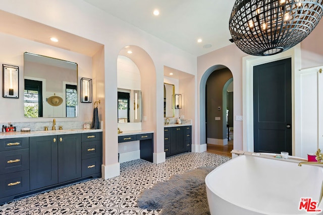 bathroom with a bathing tub, vanity, and tile patterned floors